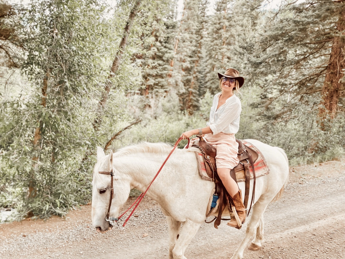 Brisa riding a white horse through the forest